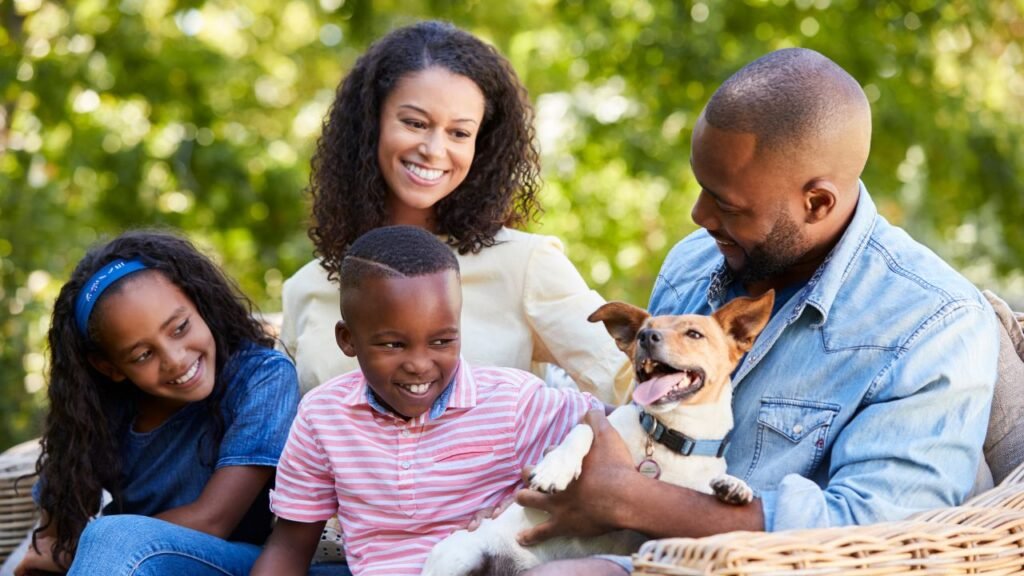 A family happily playing with their Beagle while sitting on a bench outdoors. 